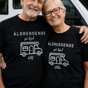 Svart t-shirt med texten ”Äldreboende på hjul” framför husvagn på camping