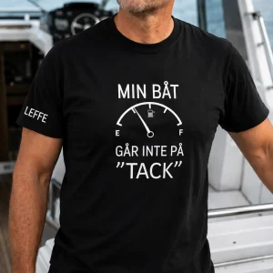 svart t-shirt med vitt tryck ”Min båt går inte på tack”, stående på motorbåt.