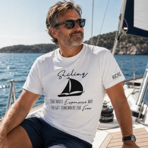 Personlig seglar-t-shirt med texten "Sailing – The Most Expensive Way To Get Somewhere For Free" och eget namn på ärmen.
