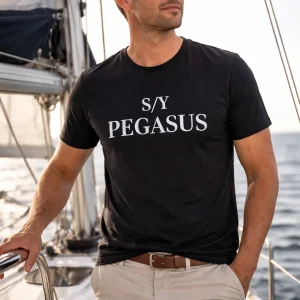 Stilren svart t-shirt med vit text ”ditt eget båtnamn", fotograferad på segelbåt – en tidlös design för båtägare och seglingsentusiaster.